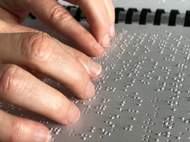 photo of fingers reading a braille book